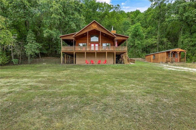 back of house featuring an outbuilding, a yard, and a deck