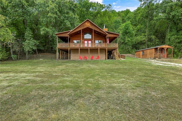 back of house featuring stairway, a lawn, a deck, an outdoor structure, and a view of trees