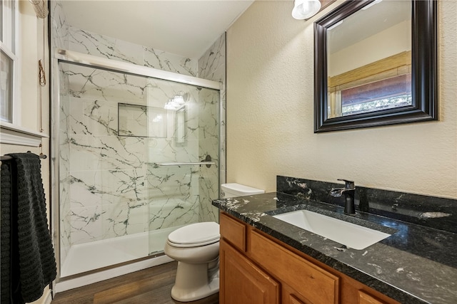 bathroom featuring vanity, hardwood / wood-style flooring, toilet, and a shower with shower door