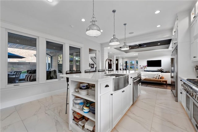 kitchen with hanging light fixtures, white cabinetry, a center island with sink, and high quality appliances