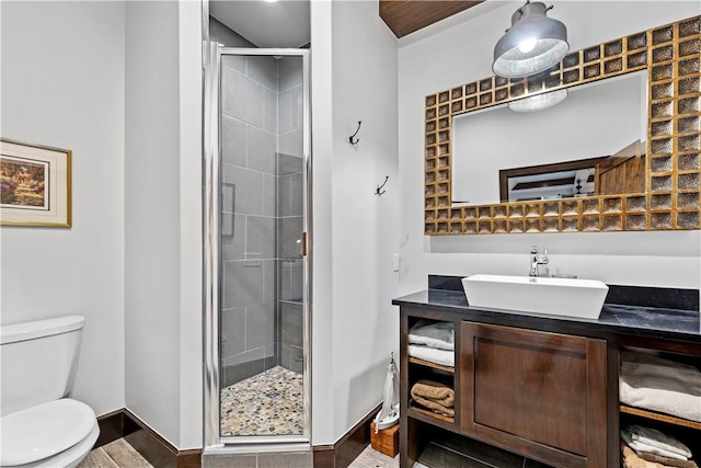 bathroom featuring vanity, a shower with door, and toilet