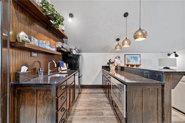 bar featuring sink, decorative light fixtures, dark brown cabinets, and vaulted ceiling