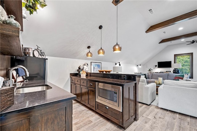 kitchen featuring stainless steel microwave, pendant lighting, sink, a center island, and dark brown cabinetry