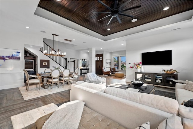 living room with parquet flooring, ornate columns, wooden ceiling, a tray ceiling, and ceiling fan with notable chandelier