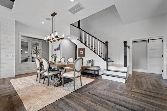 dining room with a barn door, a chandelier, and dark parquet floors