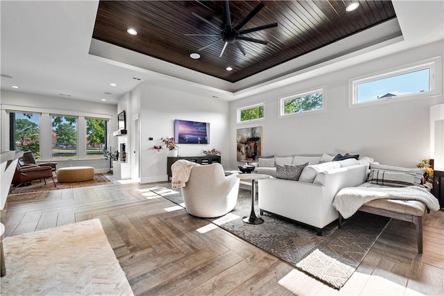 living room featuring a tray ceiling, a wealth of natural light, and wooden ceiling