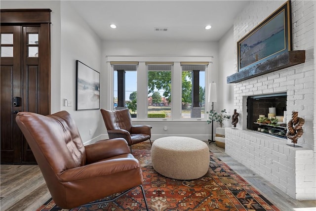 living room with hardwood / wood-style floors and a brick fireplace