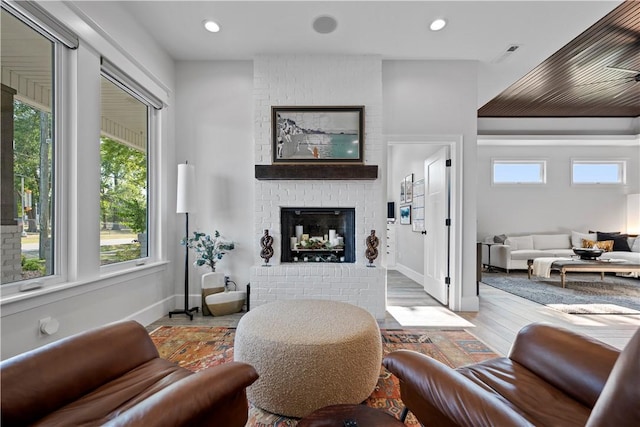 living room featuring a brick fireplace and light hardwood / wood-style flooring