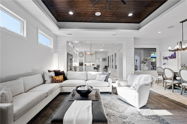 living room featuring dark parquet floors, a notable chandelier, wood ceiling, and a tray ceiling