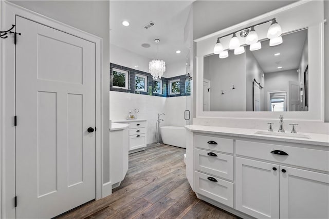 bathroom with vanity, a tub to relax in, and wood-type flooring