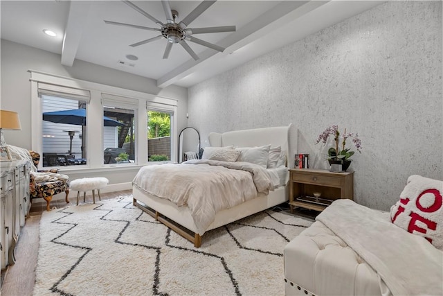 bedroom with beamed ceiling, light wood-type flooring, and ceiling fan