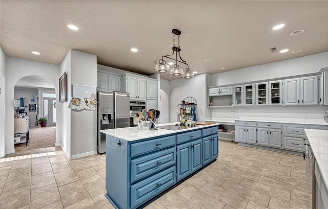 kitchen featuring a center island, black electric stovetop, stainless steel fridge with ice dispenser, arched walkways, and blue cabinets