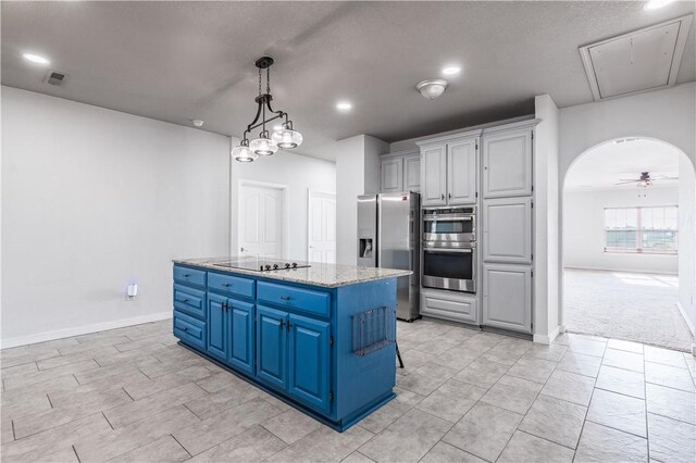 kitchen with visible vents, arched walkways, appliances with stainless steel finishes, blue cabinets, and a center island