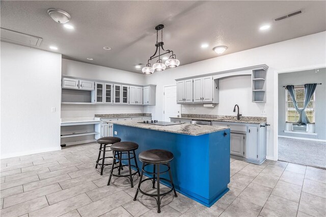 kitchen with visible vents, a center island, a breakfast bar, black electric cooktop, and open shelves