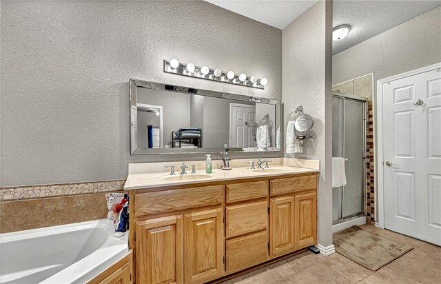 bathroom with double vanity, a textured wall, a stall shower, and a sink