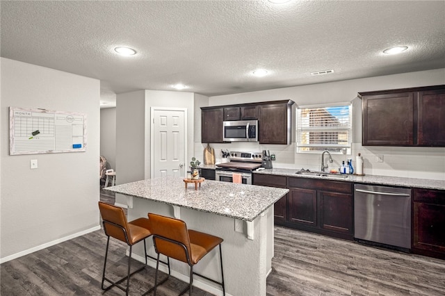 kitchen featuring sink, stainless steel appliances, a center island, and hardwood / wood-style flooring