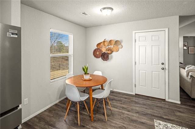 dining area with a textured ceiling and dark hardwood / wood-style floors