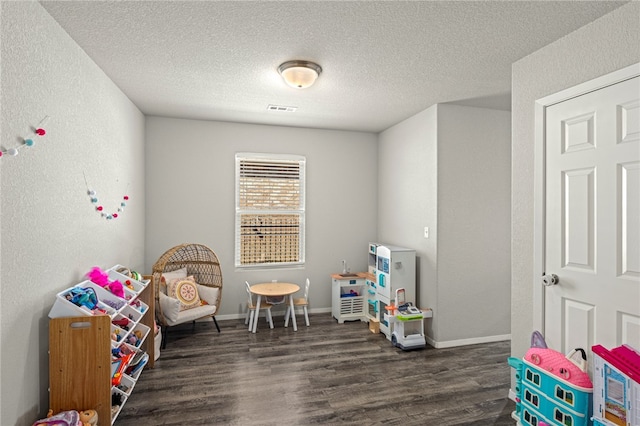 playroom with dark wood-type flooring and a textured ceiling