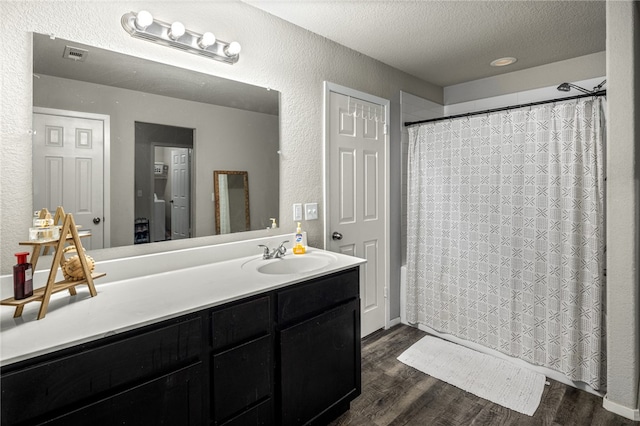 bathroom with a textured ceiling, vanity, and hardwood / wood-style floors