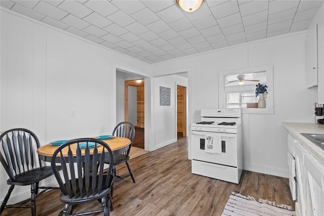 kitchen featuring light hardwood / wood-style floors, white cabinets, ceiling fan, and white gas range oven