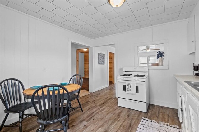 156 Main, Colcord, OK 74338 - kitchen with white gas range oven, wood finished floors, white cabinetry, light countertops, and ornamental molding