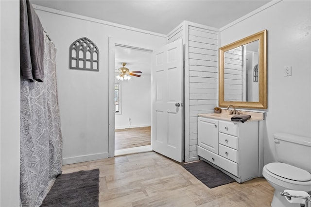 bathroom featuring toilet, ceiling fan, ornamental molding, hardwood / wood-style flooring, and vanity