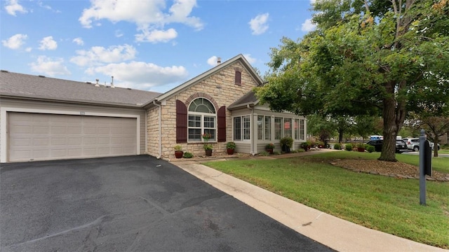 view of front of house with roof with shingles, an attached garage, a front yard, stone siding, and driveway