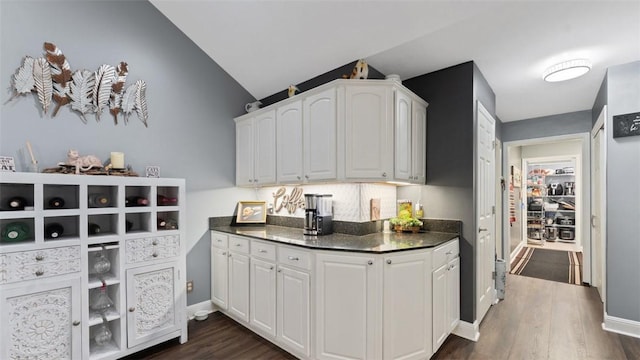 kitchen with dark wood-style flooring, baseboards, vaulted ceiling, white cabinets, and dark countertops