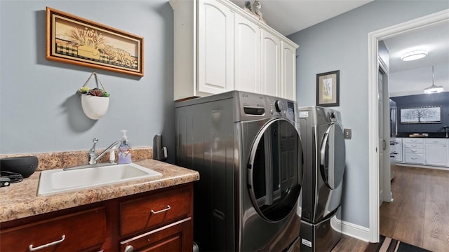 laundry area with separate washer and dryer, dark wood-style flooring, a sink, baseboards, and cabinet space