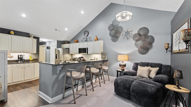 kitchen featuring dark countertops, open floor plan, high quality fridge, a peninsula, and a kitchen bar