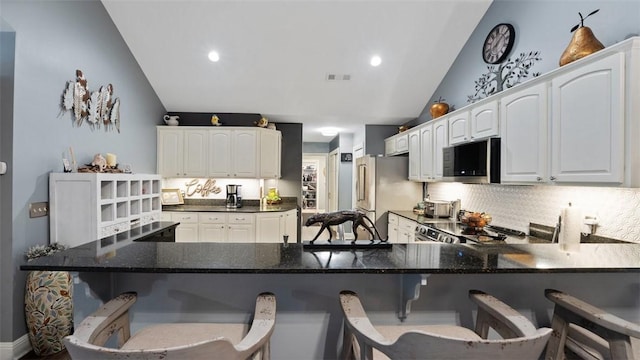 kitchen with lofted ceiling, white cabinetry, a kitchen breakfast bar, a peninsula, and high end refrigerator