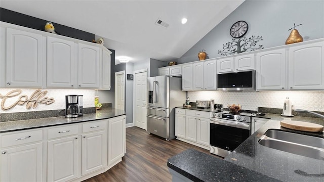 kitchen featuring dark wood-style flooring, dark countertops, backsplash, appliances with stainless steel finishes, and white cabinetry