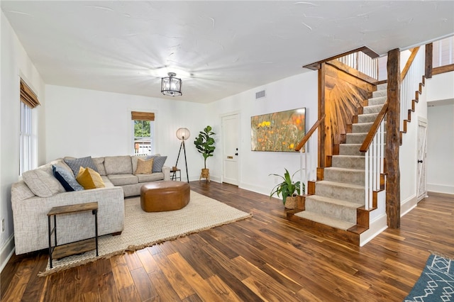 living room featuring baseboards, visible vents, stairway, wood finished floors, and an inviting chandelier