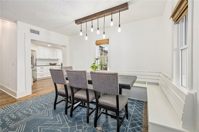 dining room with dark wood-type flooring, visible vents, and baseboards