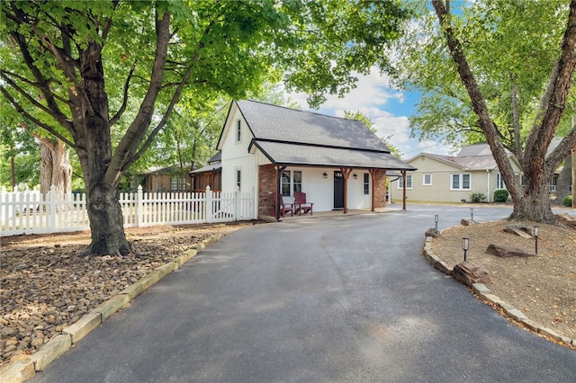 view of front of property with aphalt driveway, brick siding, fence, and roof with shingles