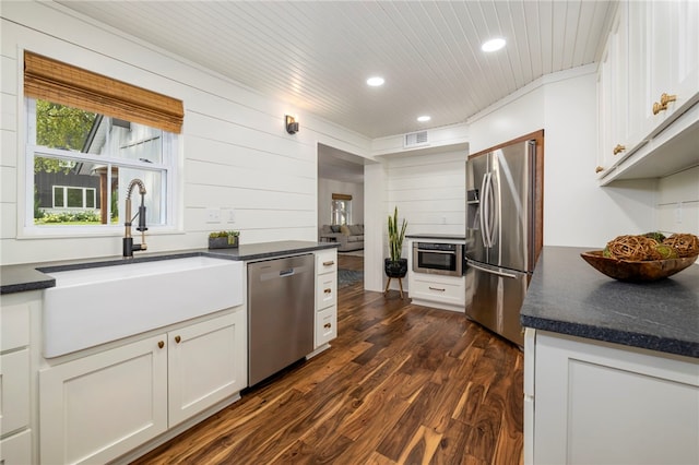 kitchen with visible vents, dark wood finished floors, dark countertops, stainless steel appliances, and a sink