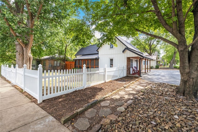 exterior space featuring a shingled roof and a fenced front yard