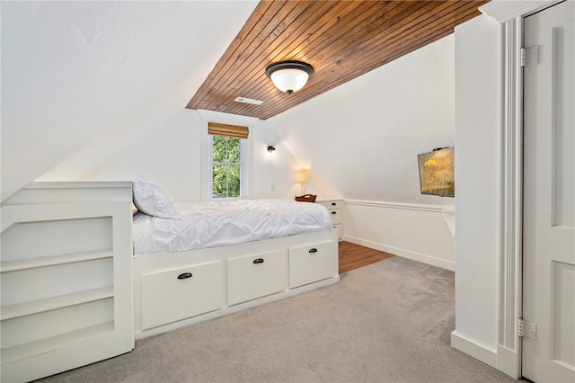 unfurnished bedroom featuring wooden ceiling, light carpet, vaulted ceiling, and wainscoting