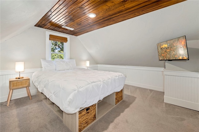 carpeted bedroom featuring lofted ceiling, a wainscoted wall, and wood ceiling