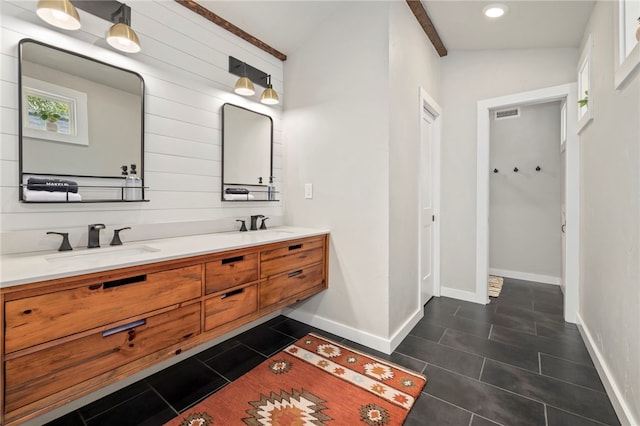 bathroom with baseboards, double vanity, a sink, and tile patterned floors