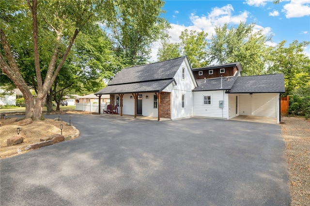 exterior space featuring brick siding, driveway, and roof with shingles