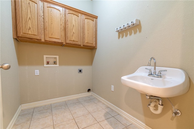 clothes washing area featuring electric dryer hookup, washer hookup, light tile patterned floors, and cabinets