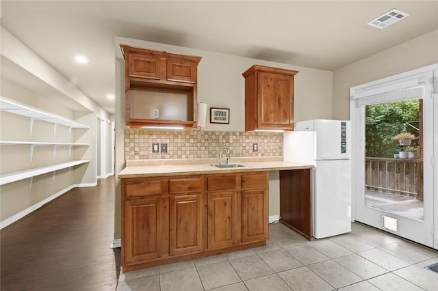 kitchen featuring tasteful backsplash, white refrigerator, sink, and light hardwood / wood-style flooring