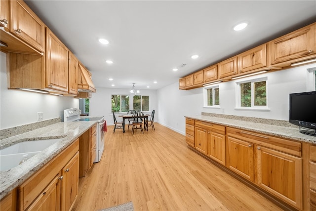 kitchen featuring white range with electric cooktop, light stone countertops, a chandelier, and light wood-type flooring