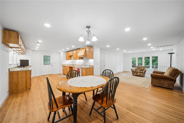 dining room featuring light wood-type flooring, a notable chandelier, and sink