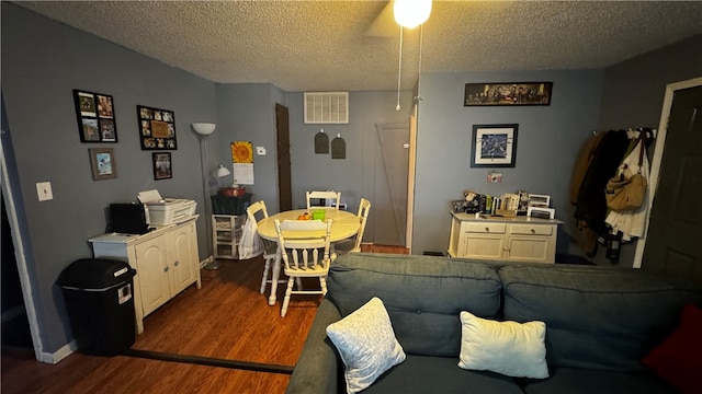 living room with ceiling fan, a textured ceiling, and dark hardwood / wood-style flooring