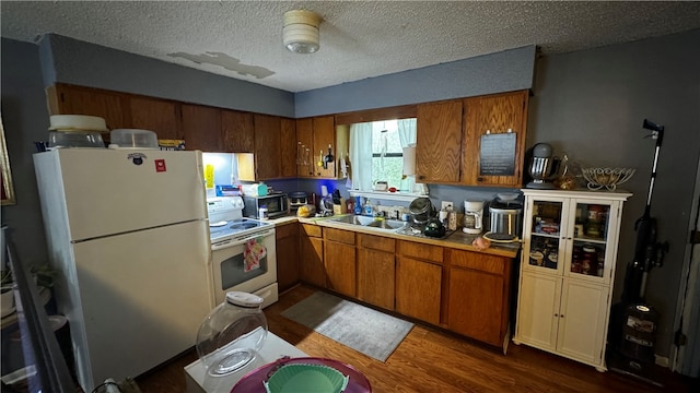 kitchen with hardwood / wood-style flooring, sink, a textured ceiling, and white appliances