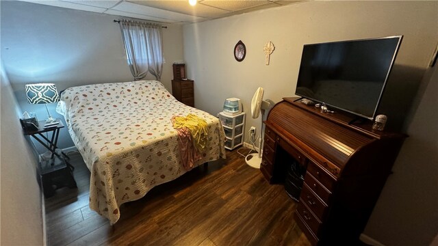 bedroom featuring a drop ceiling and dark hardwood / wood-style flooring