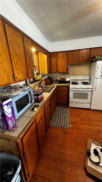 kitchen with a textured ceiling, white appliances, dark wood-type flooring, and sink