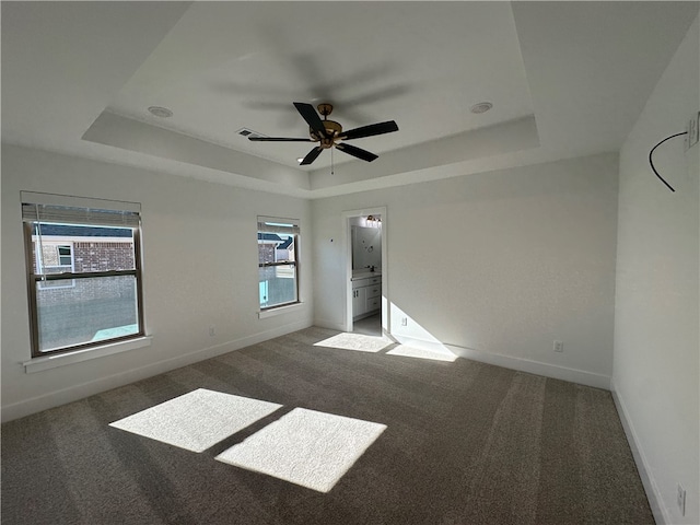 empty room featuring a healthy amount of sunlight, carpet floors, and a tray ceiling